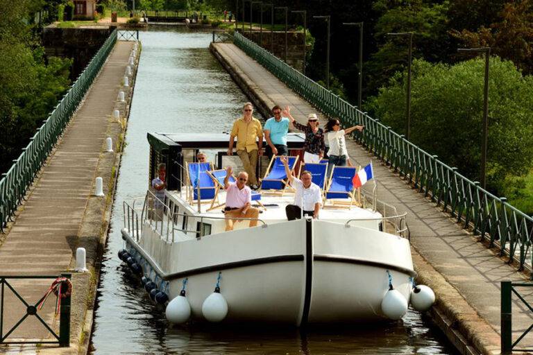 Eine Familie sitzt an Deck eines Hausbootes auf einem Fluss