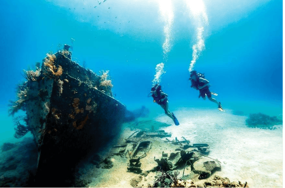 Two snorkelers exploring colorful coral reefs and tropical fish in crystal-clear waters of the Bahamas.