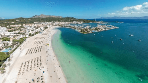 Marina von Alcúdia im Norden Mallorcas mit modernen Segelyachten, kristallklarem Wasser und Blick auf die Küstenlandschaft. Perfekter Hafen für Yachtcharter und Segeltörns rund um Mallorca.
