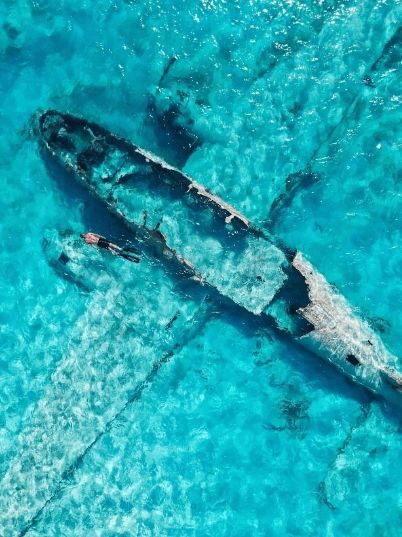 Sunken shipwreck in clear turquoise waters of the Bahamas, perfect for snorkeling and underwater exploration.