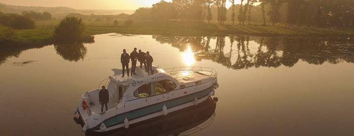 Mehrere Personen bei Sonnenuntergang auf einem Hausboot 