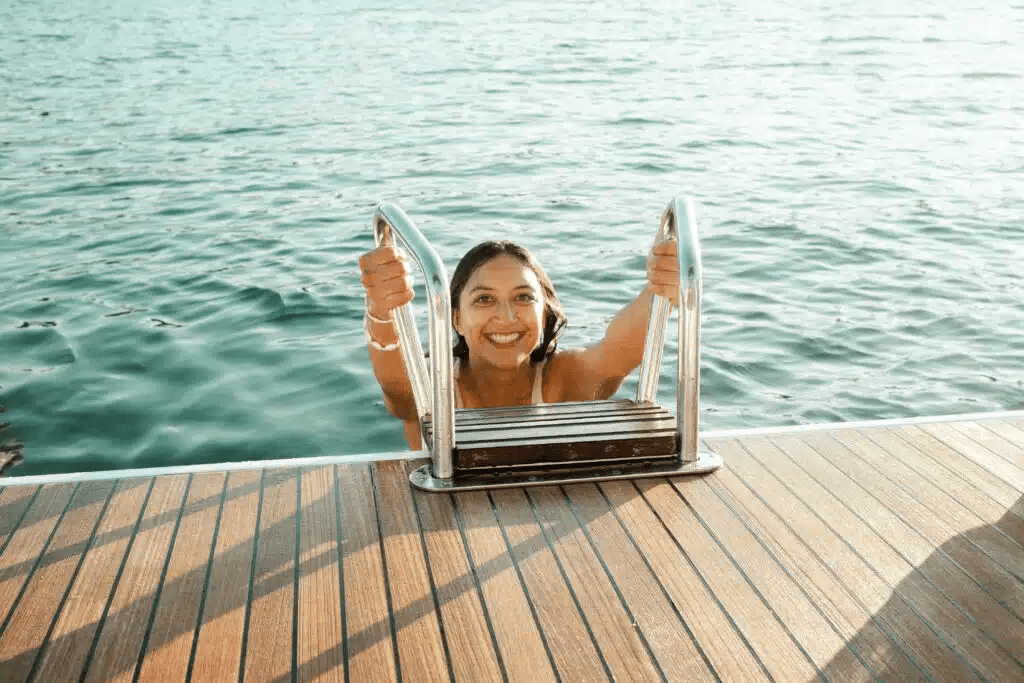 Seglerin steigt vom Boot ins Meer – Badepause beim Segelurlaub in Griechenland